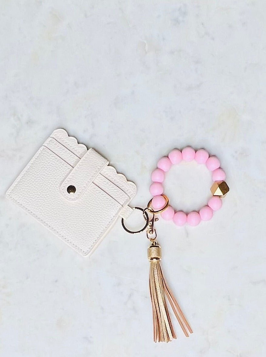 Always on the go? The Pink/Gold O Wristband Keychain has got you covered! Made with 15-mm silicone beads, a split ring, clasp, and leather tassel, it's the perfect companion for life on-the-move. Plus, it comes with a super convenient credit card and ID holder, complete with a key ring to quickly hook up your keys. Whip it around your wrist and zoom out the door - no hassle, no fuss!